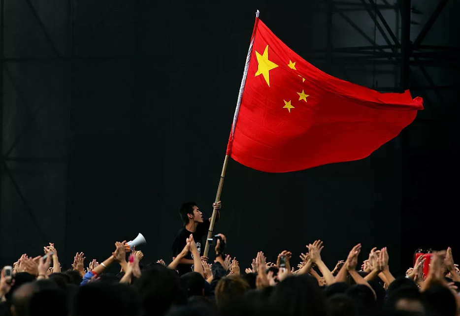 Un adolescente chino ondea una bandera nacional durante un festival para conmemorar el Día Nacional de China en Beijing, China.