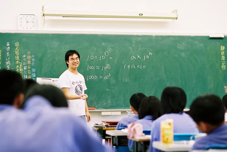 Profesor dando una lección de matemáticas a un aula llena de niños.